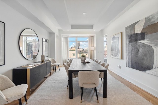 dining room with recessed lighting, a raised ceiling, baseboards, and wood finished floors