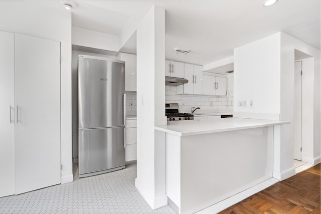 kitchen with under cabinet range hood, decorative backsplash, appliances with stainless steel finishes, white cabinetry, and a sink