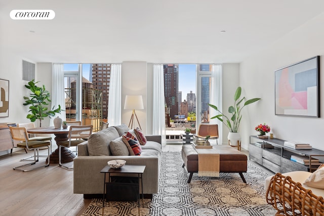 living room with a wall of windows, wood finished floors, visible vents, and a city view