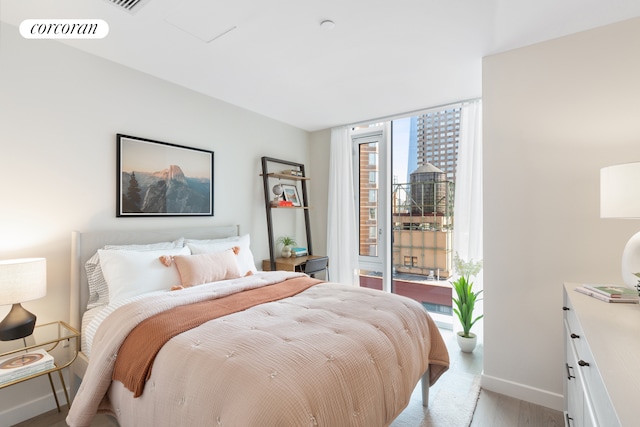 bedroom with visible vents, baseboards, access to outside, light wood-type flooring, and floor to ceiling windows