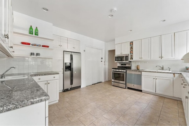 kitchen featuring stainless steel appliances, decorative backsplash, stone counters, white cabinets, and sink