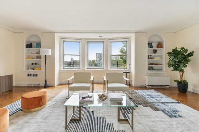 sitting room with wood-type flooring, ornamental molding, radiator heating unit, and built in features