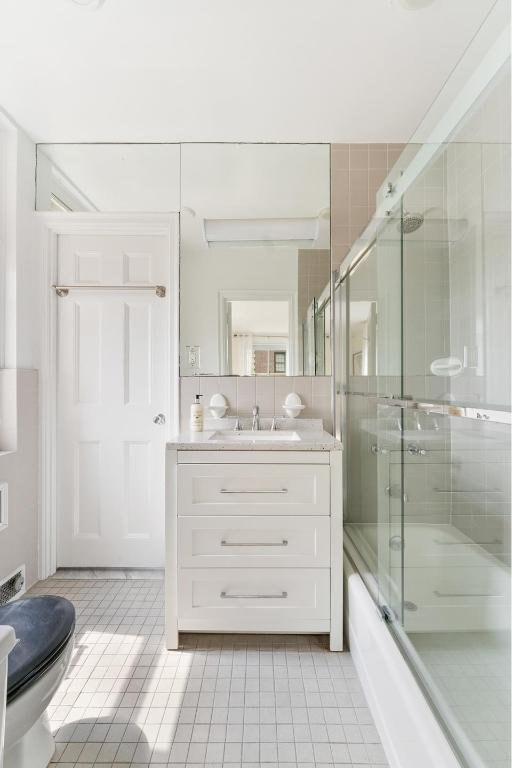 full bathroom featuring toilet, vanity, tile patterned flooring, and enclosed tub / shower combo