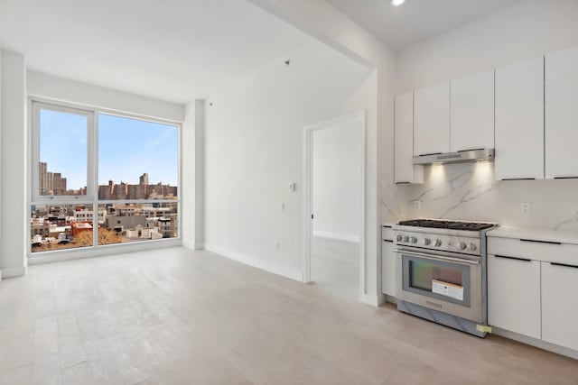 139 Bowery Unit 12B, New York City, NY 10002 - kitchen featuring high end stove, under cabinet range hood, white cabinetry, backsplash, and recessed lighting
