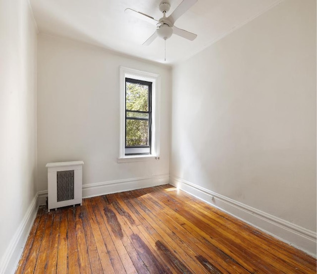 unfurnished room featuring dark wood-type flooring, ceiling fan, and heating unit