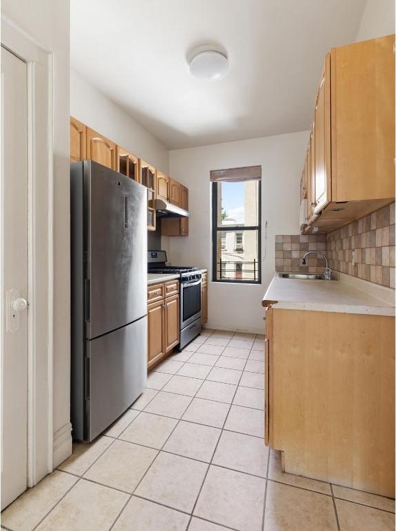 kitchen featuring stainless steel appliances, sink, light tile patterned floors, and decorative backsplash