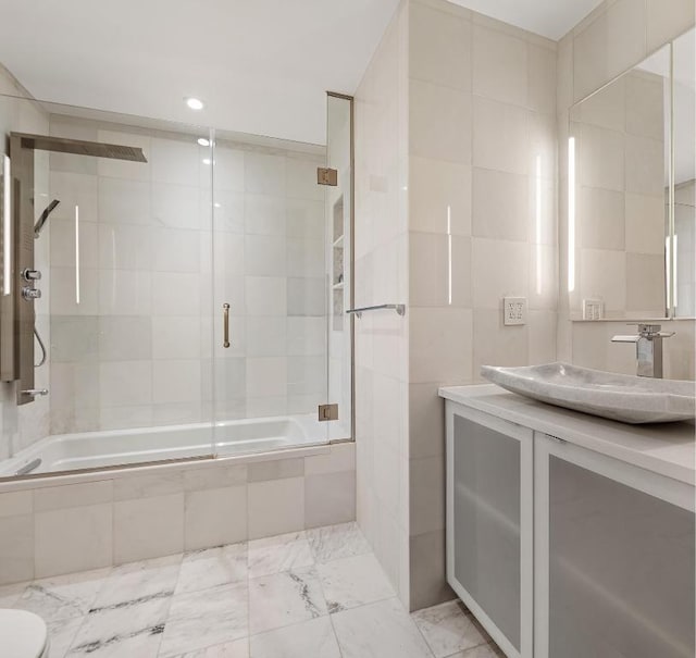 bathroom featuring vanity, bath / shower combo with glass door, and tile walls