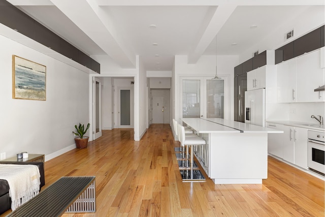 315 7th Ave Unit 3D, New York City, NY 10001 - kitchen with built in fridge, oven, light countertops, a breakfast bar, and pendant lighting