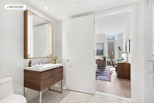 bathroom featuring floor to ceiling windows, hardwood / wood-style flooring, toilet, and vanity