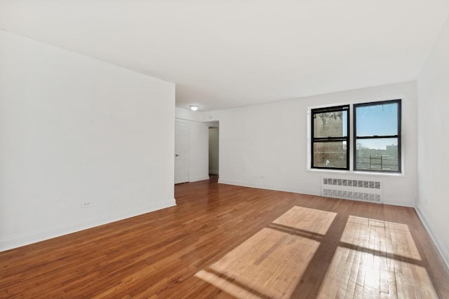 unfurnished room with radiator heating unit and wood-type flooring