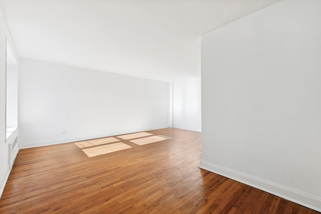 spare room with wood-type flooring and baseboards