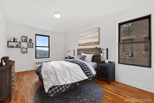 bedroom featuring radiator heating unit, baseboards, and light wood-style flooring