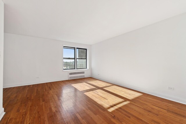 unfurnished room with radiator, baseboards, and hardwood / wood-style floors