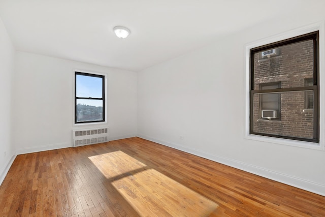 spare room featuring cooling unit, radiator heating unit, baseboards, and hardwood / wood-style floors