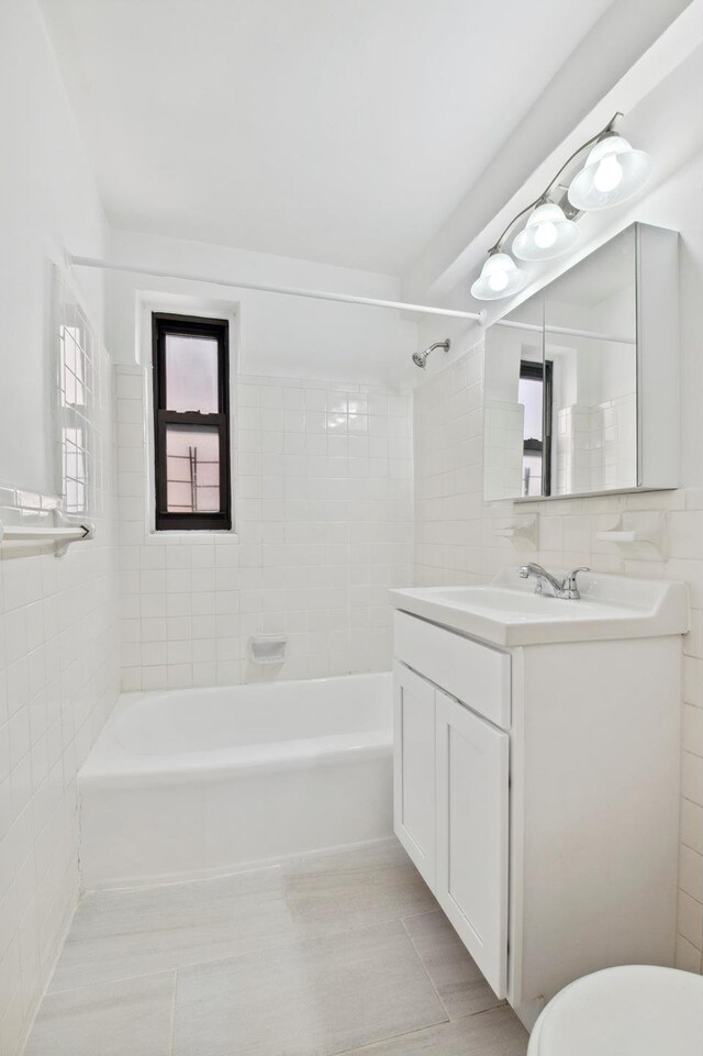 full bath featuring toilet, vanity, tile patterned flooring, shower / bathtub combination, and tile walls