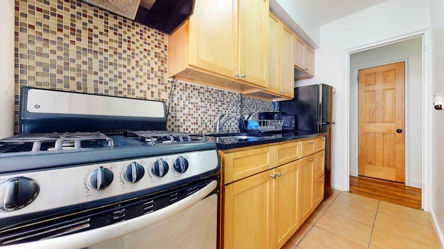 2191 Bolton St Unit 5E, New York City, NY 10462 - kitchen featuring light brown cabinets, a sink, dark countertops, stainless steel range with gas cooktop, and decorative backsplash