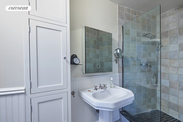 bathroom featuring wainscoting, a sink, and a shower stall