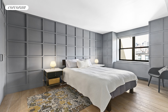 bedroom featuring visible vents, hardwood / wood-style floors, and a decorative wall