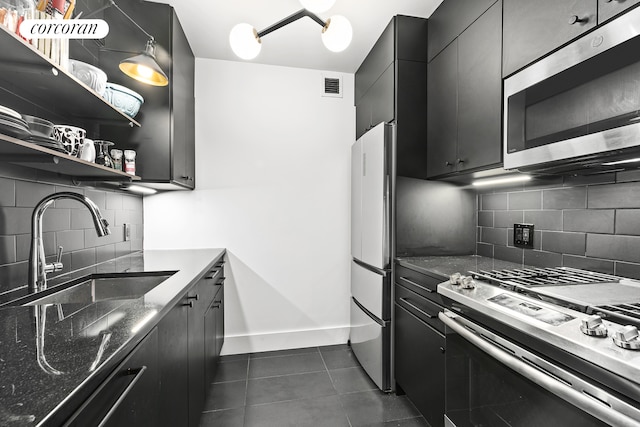 kitchen featuring visible vents, a sink, appliances with stainless steel finishes, dark cabinetry, and dark tile patterned flooring