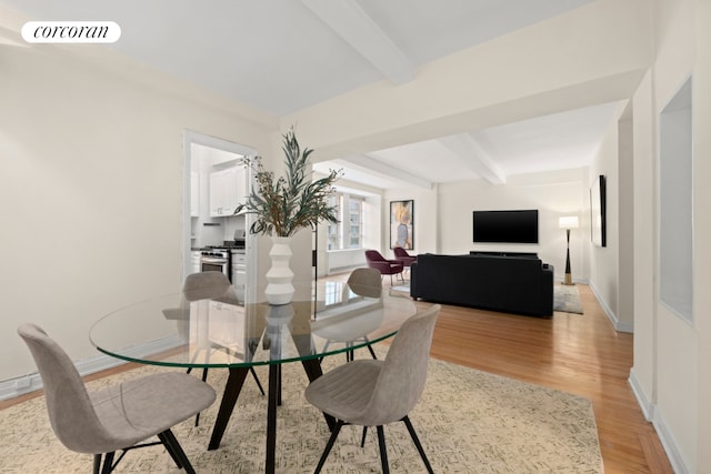 dining area featuring light wood-type flooring and beamed ceiling