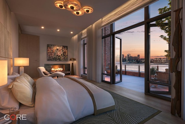 bedroom featuring a wall of windows, wood-type flooring, multiple windows, and access to outside