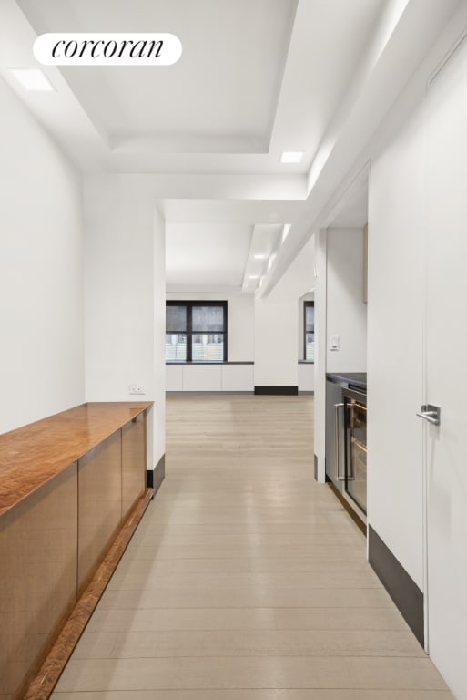 hallway with a tray ceiling and light hardwood / wood-style flooring