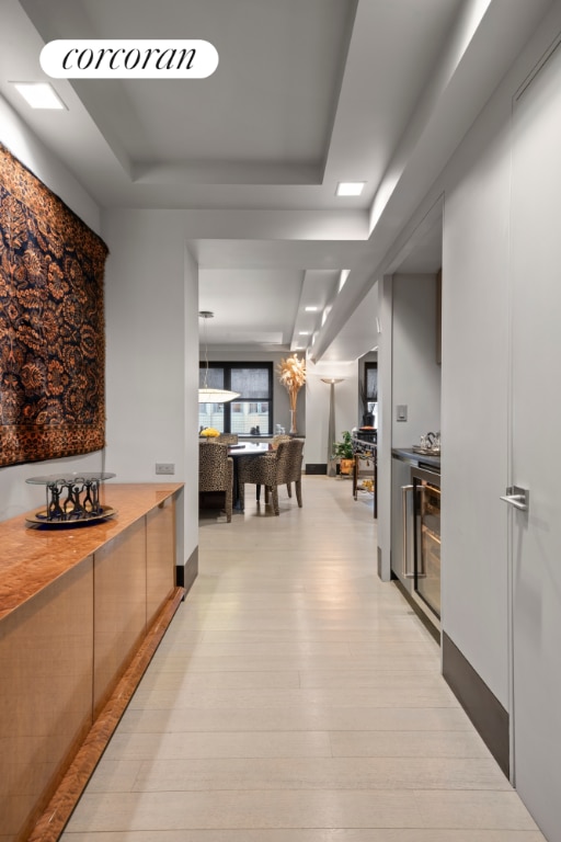 hallway featuring light wood-type flooring and a tray ceiling