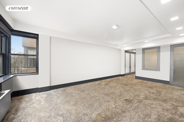 carpeted empty room featuring a tray ceiling