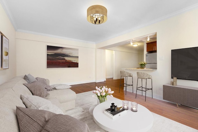 living room featuring rail lighting, hardwood / wood-style floors, and crown molding