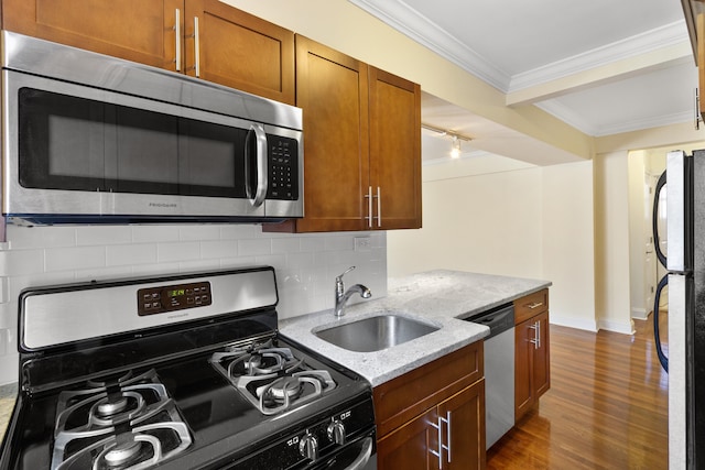 kitchen featuring backsplash, appliances with stainless steel finishes, ornamental molding, a sink, and wood finished floors