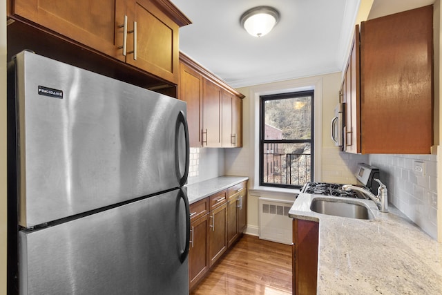 kitchen with light wood finished floors, radiator, decorative backsplash, ornamental molding, and freestanding refrigerator