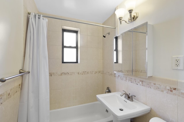 full bathroom with toilet, a sink, tile walls, and shower / bathtub combination with curtain