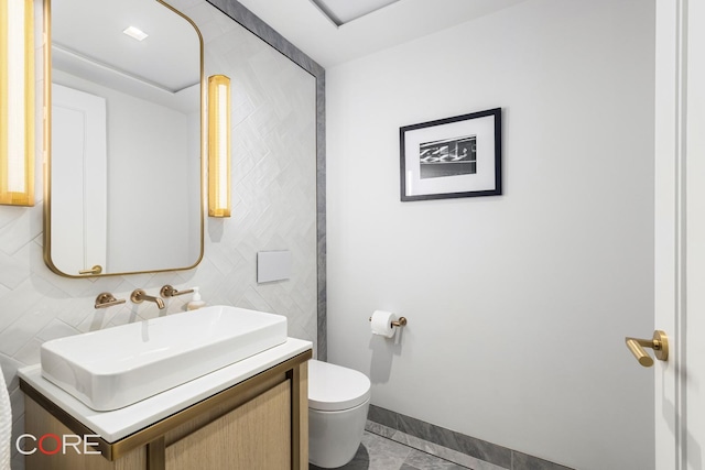 bathroom with tasteful backsplash, baseboards, vanity, and toilet