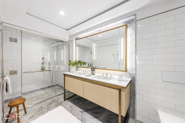 full bath featuring a sink, a stall shower, double vanity, and tile walls