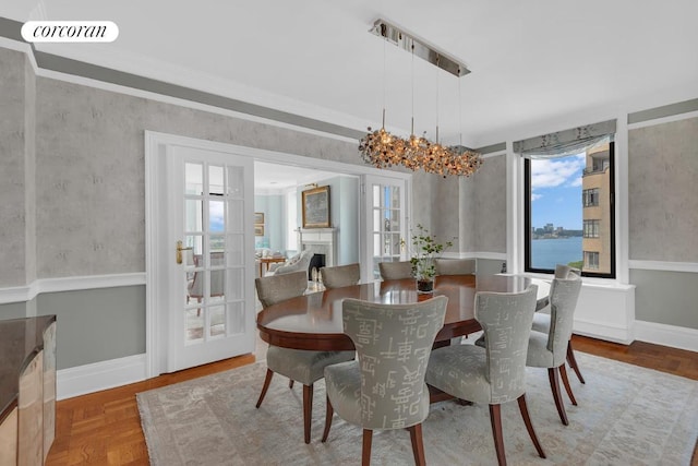 dining space featuring a chandelier, ornamental molding, parquet floors, and a water view