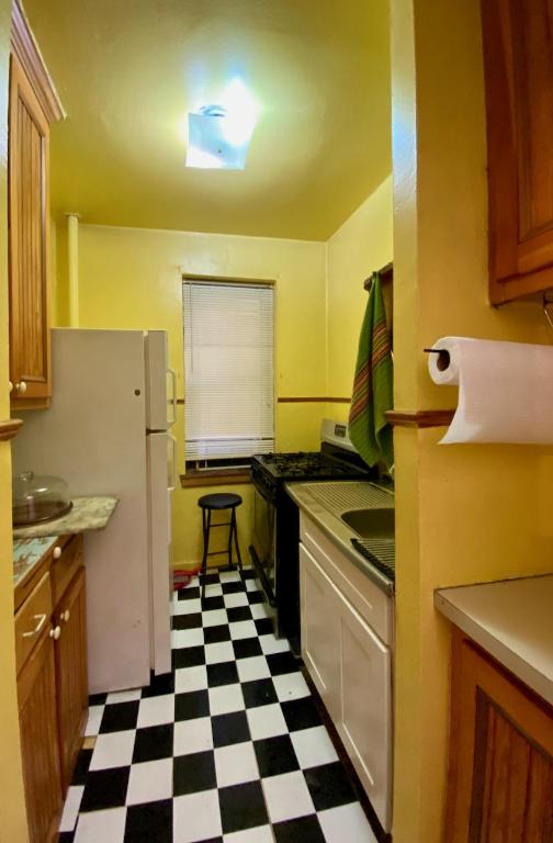 kitchen featuring brown cabinetry, gas range, dark floors, freestanding refrigerator, and light countertops