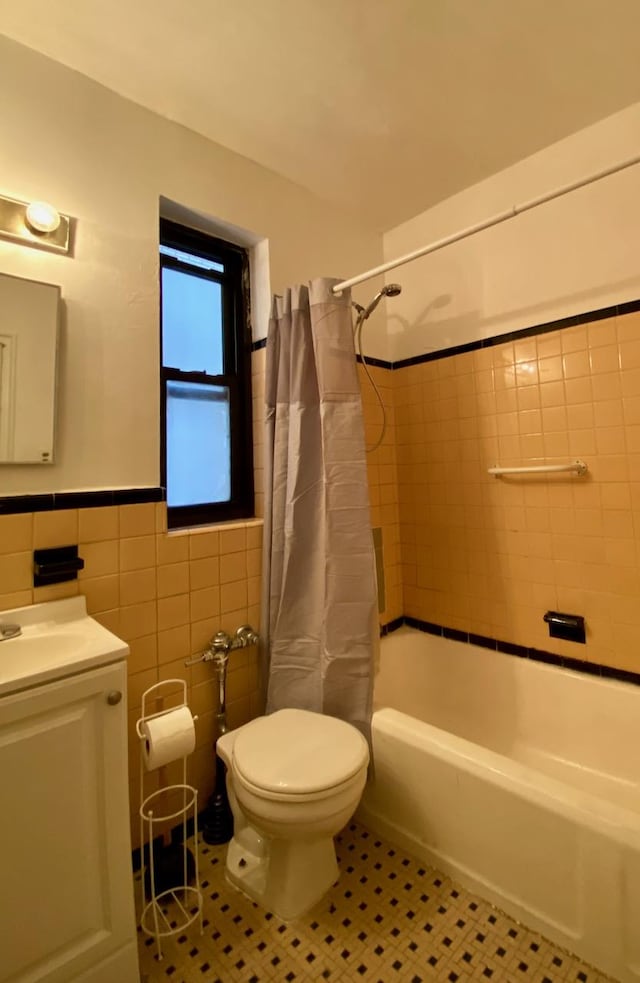 251 Seaman Ave Unit 2-H, New York City, NY 10034 - bathroom featuring tile walls, vanity, shower / tub combo with curtain, tile patterned floors, and a wainscoted wall