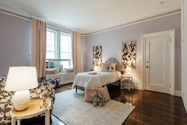 bedroom with crown molding, radiator heating unit, and dark hardwood / wood-style floors