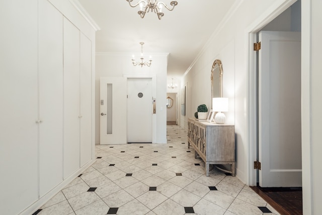 tiled entrance foyer featuring ornamental molding and a chandelier