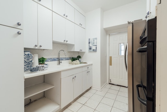 kitchen featuring light tile patterned floors, decorative backsplash, sink, and white cabinets