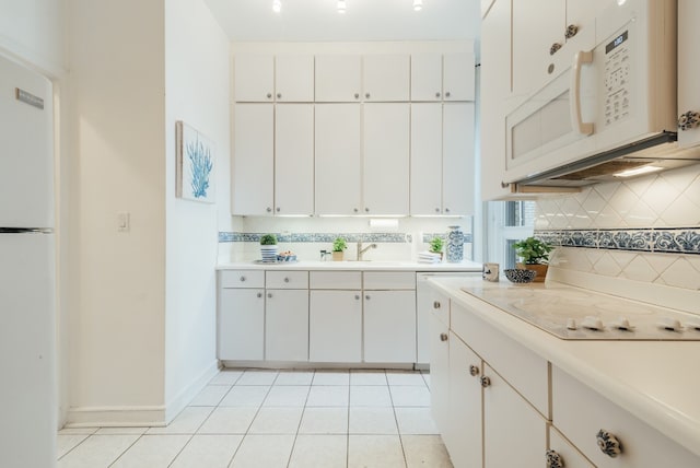 kitchen with white cabinetry, light tile patterned floors, and white appliances