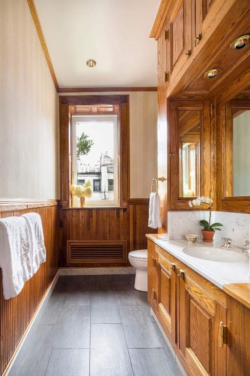 bathroom with crown molding, tile patterned flooring, wooden walls, vanity, and toilet