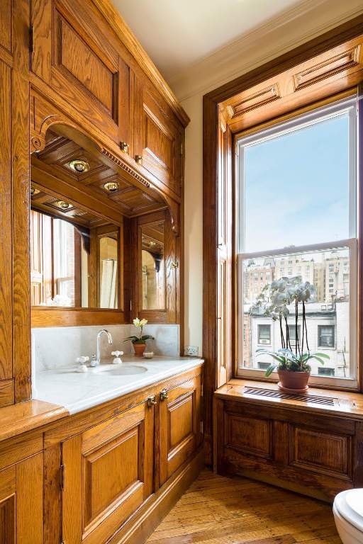 kitchen with wall chimney exhaust hood, crown molding, pendant lighting, a kitchen island with sink, and decorative backsplash