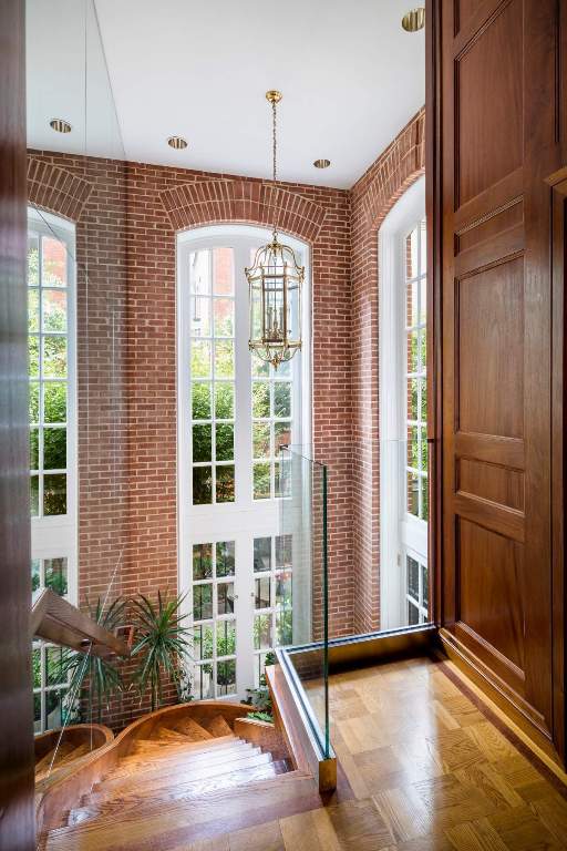 unfurnished living room with light parquet floors, ornamental molding, a brick fireplace, and a chandelier