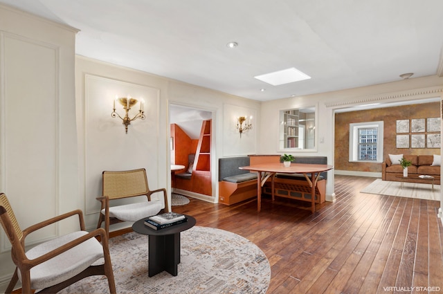 living area featuring a skylight, baseboards, and hardwood / wood-style flooring