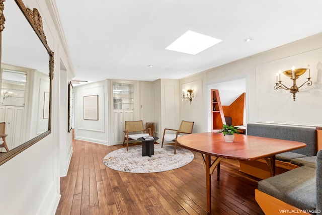 dining area with hardwood / wood-style floors and a skylight