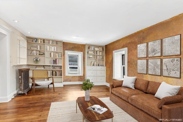 living area featuring cooling unit, baseboards, and hardwood / wood-style flooring