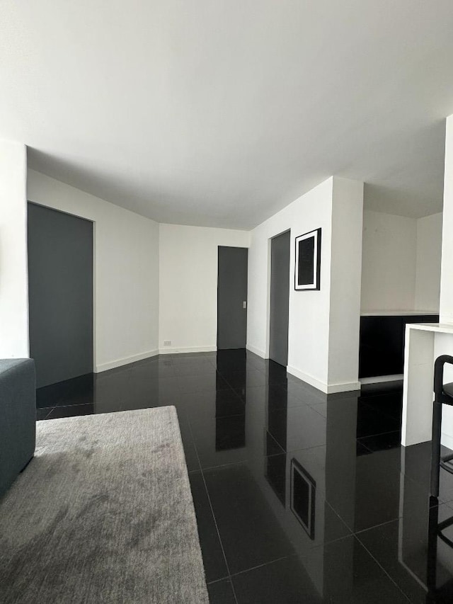 corridor with dark tile patterned flooring and baseboards