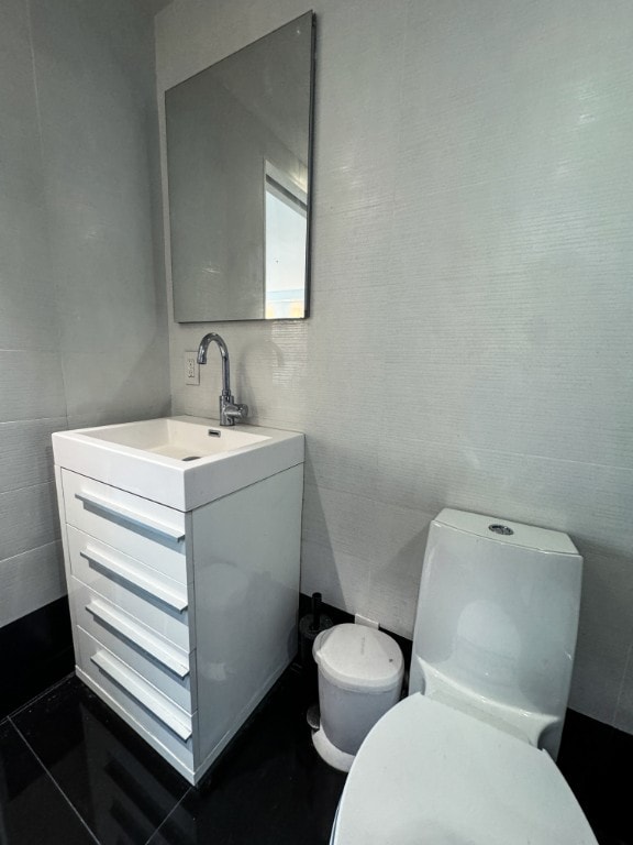 bathroom featuring tile walls, toilet, vanity, and tile patterned flooring