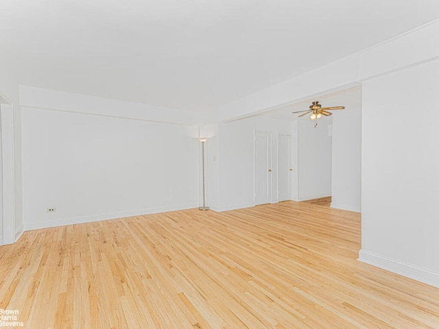 empty room featuring ceiling fan, light wood finished floors, and baseboards